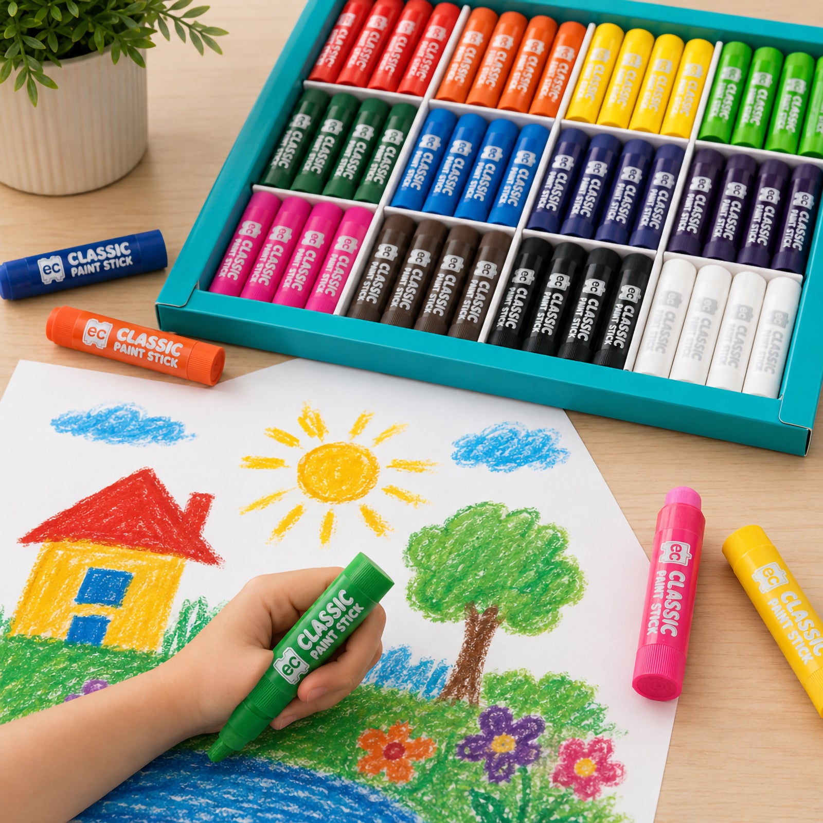 Educational Colours Classic Paint Sticks Set of 96 displayed beside a child creating a bright outdoor landscape drawing with vibrant colours on a tabletop.