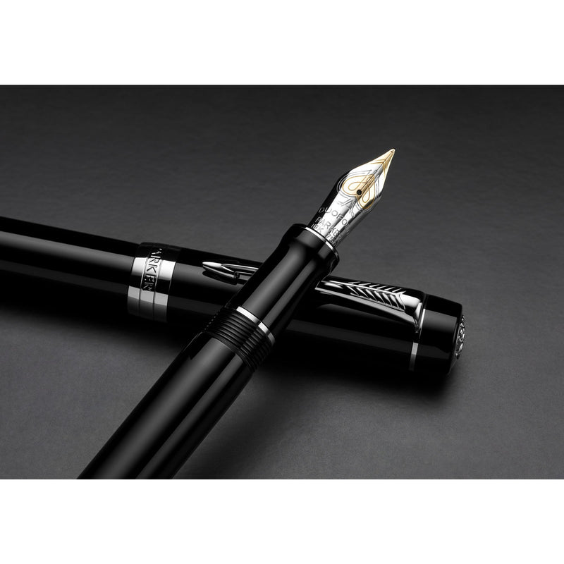 Black Duofold fountain pen with silver-tone trims lying over its cap on a dark background, two-tone gold nib facing up