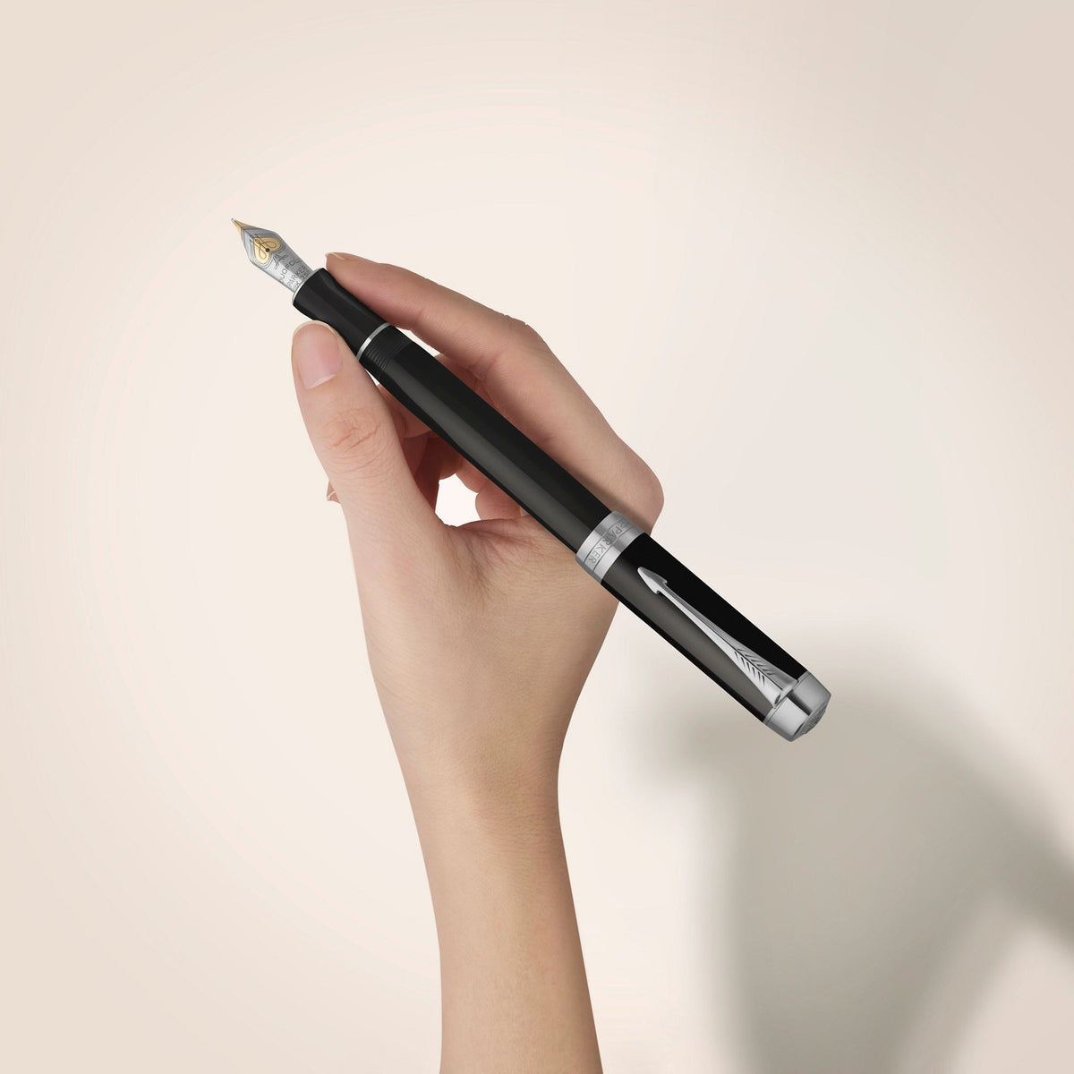 A hand holding the black Duofold Classic fountain pen with palladium trims against a pale wall