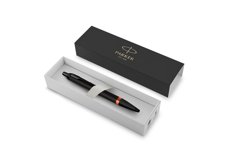 Parker IM Vibrant Rings Flame Orange ballpoint pen resting in an open Parker gift box, with a white tray and a black lid printed with the Parker logo