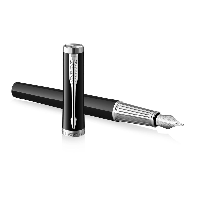 Uncapped Ingenuity fountain pen crossed over its cap, showing the ribbed chrome section and steel nib