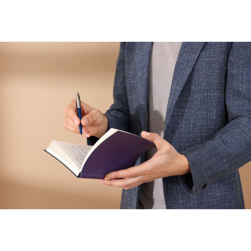 Man in a blazer writing in a purple notebook with a Royal Blue Jotter ballpoint