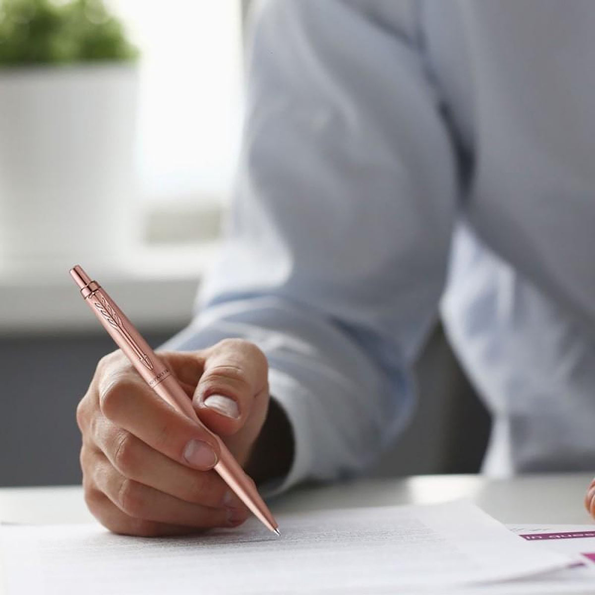 Hand writing on a document with a rose gold Jotter XL ballpoint, shirt sleeve in the background