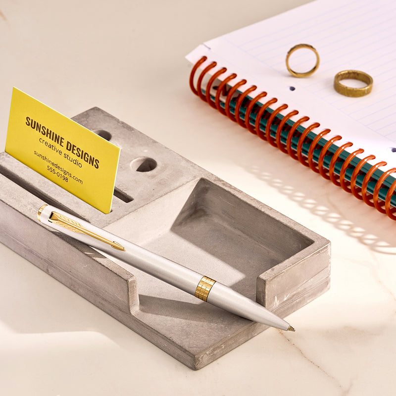 Chrome Meridian ballpoint in a styled desk setting, showing the gold clip and centre band