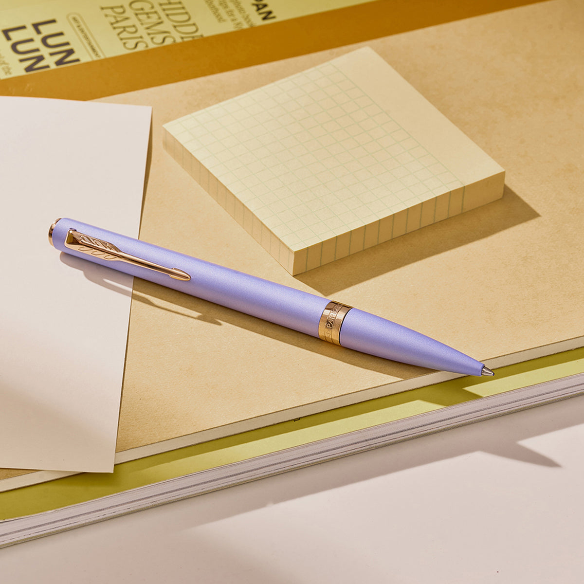 Lilac Meridian ballpoint in a styled desk setting, showing the pink gold clip and centre band
