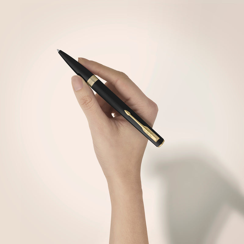 Matte black Meridian ballpoint in a styled desk setting, showing the gold clip and centre band