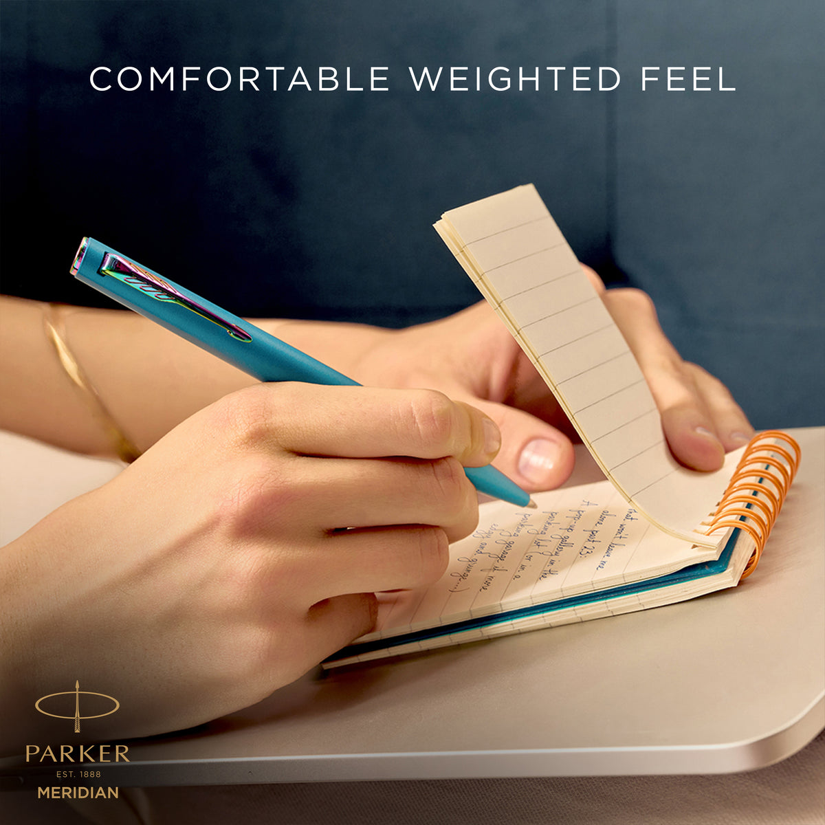 Hand writing with the teal Meridian ballpoint, captioned comfortable weighted feel