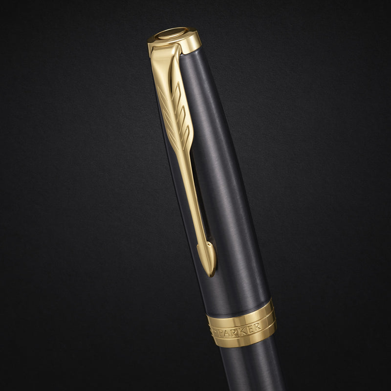 Close-up of the gold arrow clip and engraved cap band on the grey lacquer cap