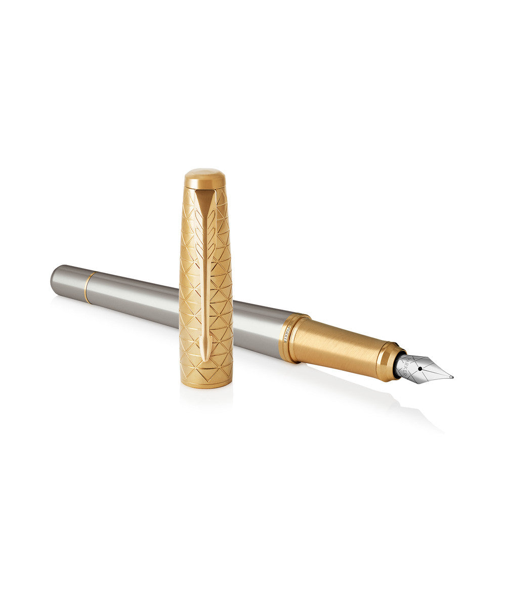 Parker Urban Premium fountain pen with the engraved gold cap stood upright beside the uncapped pen, showing the medium stainless steel nib and gold grip ring.