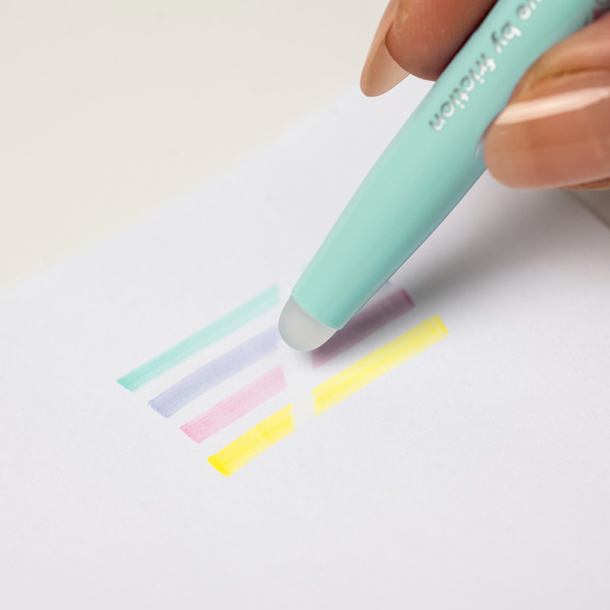 A Pilot FriXion Light Soft highlighter erasing a soft green highlight from paper, demonstrating the erasable ink.