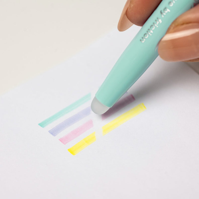 A Pilot FriXion Light Soft highlighter erasing a soft green highlight from paper, demonstrating the erasable ink.