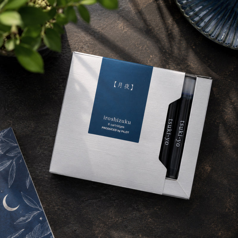 Pilot Iroshizuku Tsuki yo fountain pen ink cartridge presentation box displayed on a dark desktop with decorative greenery and moon themed stationery. The premium packaging complements the sophisticated Moonlight inspired collection.