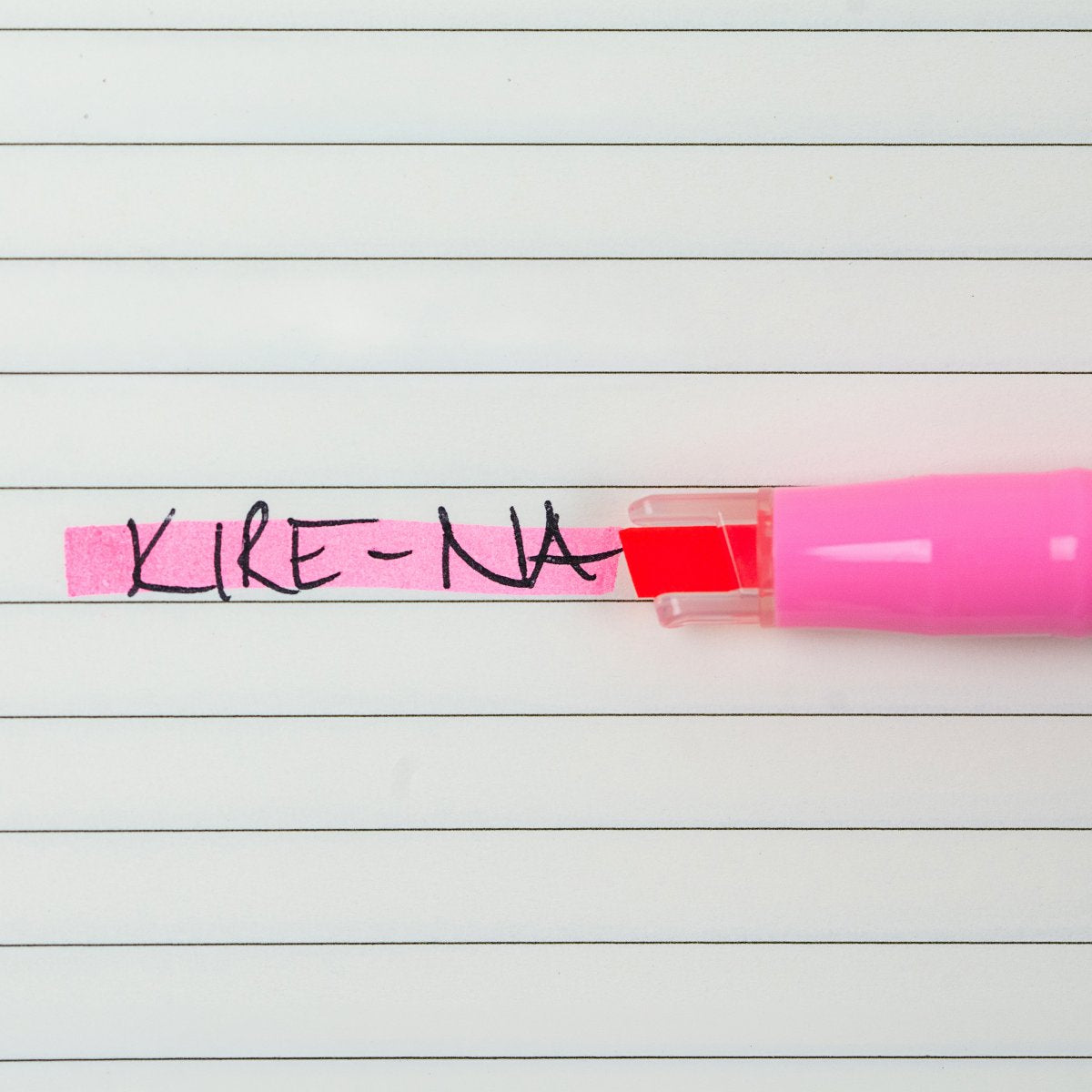 Pilot Kire-Na pink dual tip highlighter in use on a page of printed notes, the broad chisel tip laying a straight band of pink across a line of text