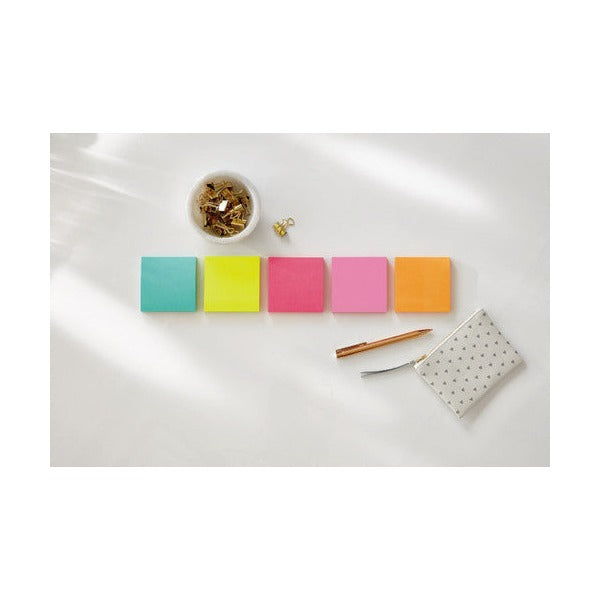 Row of five square Post-it notes in aqua, lime, pink, light pink and orange on a white table beside a pen and a dish of clips