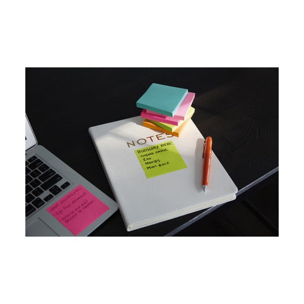 Stack of Miami coloured square Post-it notes on a white notebook with a lime note listing ideas, next to a laptop and an orange pen