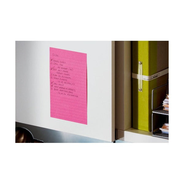 Pink lined Post-it note with a handwritten to-do list stuck to a white cupboard door beside a green binder