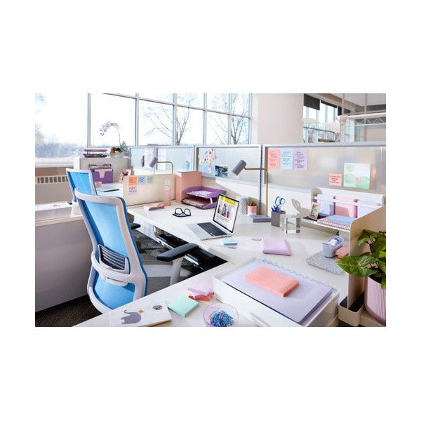 Bright open plan office desk with a blue chair, laptop and pastel notes on the partition and desk