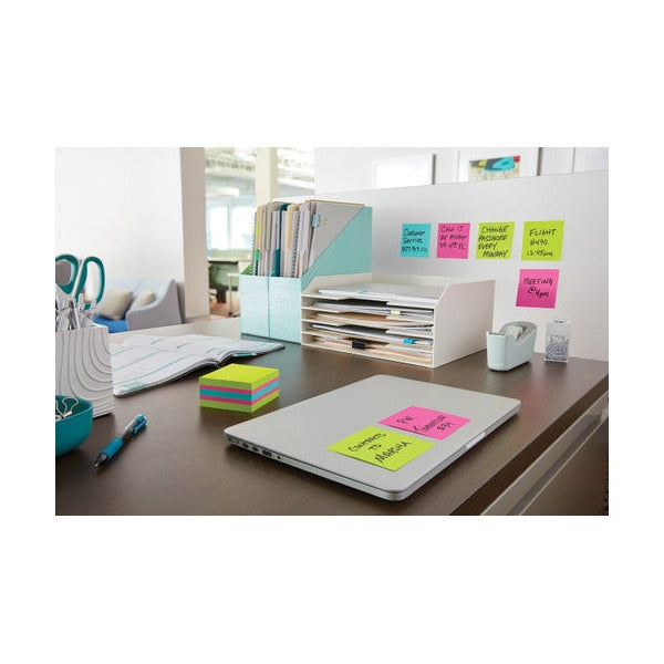 Office desk with a bright notes cube beside a laptop, colour notes stuck on the laptop and on the partition above