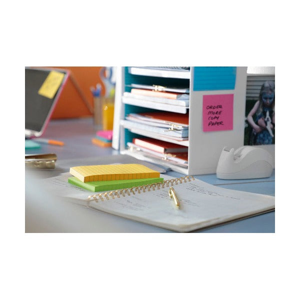 Stack of coloured lined Post-it pads on a desk with an open planner and a shelf of folders behind