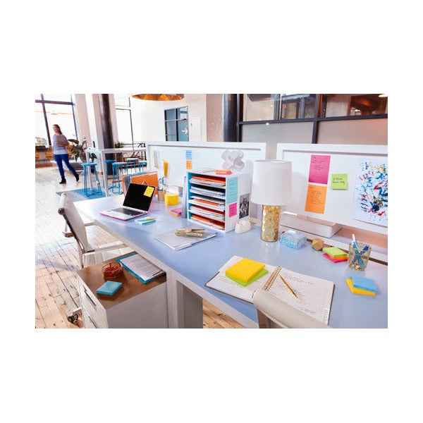 Bright open office with Super Sticky notes on a desk organiser and partition, laptop and lamp on the desk