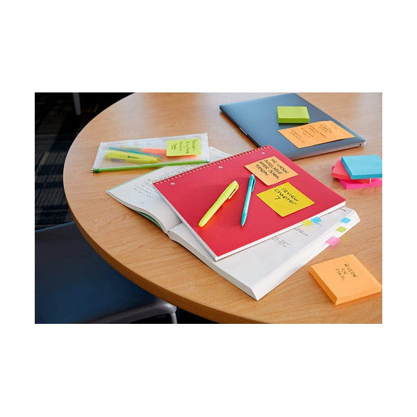 Round table with notebooks, highlighters and coloured square notes stuck on pages and the table