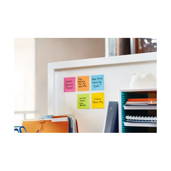 Coloured square notes with short handwritten reminders arranged on a white partition next to a file sorter