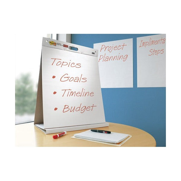 Post-it tabletop easel pad on a round meeting table with topics, goals, timeline and budget written on it and two sheets stuck to the wall