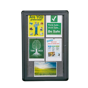 Quartet enclosed fabric notice board shown portrait, a dark graphite frame with rounded corners around grey fabric, holding safety posters, a Think Green poster and a green field photograph behind the door