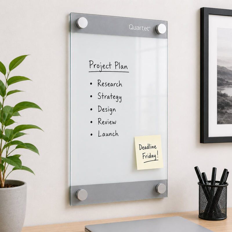 Quartet Infinity Custom Glassboard 279 x 432mm installed in a stylish workspace displaying a project planning checklist with a reminder note attached using the magnetic glass surface. The floating frameless design complements modern office interiors while supporting organised daily planning.