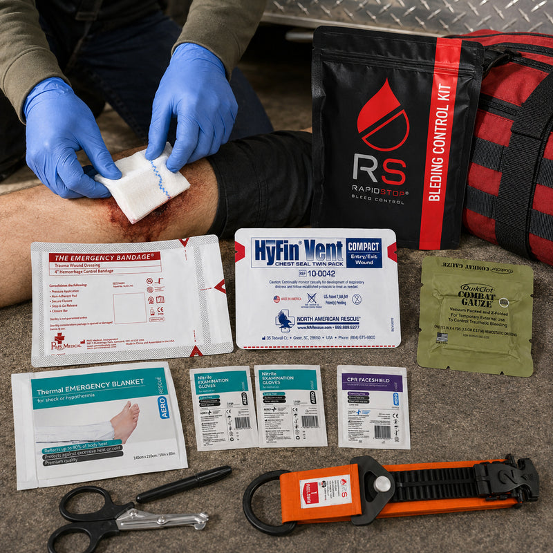 RapidStop Bleed Control Medium Pack displayed during a simulated emergency response with a gloved responder treating a leg injury. The black and red RapidStop pouch sits beside the QuikClot Combat Gauze, HyFin Vent Compact chest seal, emergency trauma bandage, thermal emergency blanket, nitrile gloves, CPR faceshield, trauma shears, marker and orange RapidStop tourniquet.
