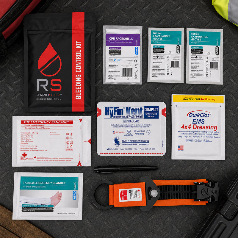Complete RapidStop Medium Bleed Control Kit arranged on a dark industrial surface. The organised layout displays the RapidStop pouch, QuikClot EMS 4x4 Dressing, HyFin Vent Compact chest seal twin pack, emergency trauma bandage, CPR faceshield, two nitrile examination glove packs, thermal emergency blanket, marker and orange RapidStop tourniquet.