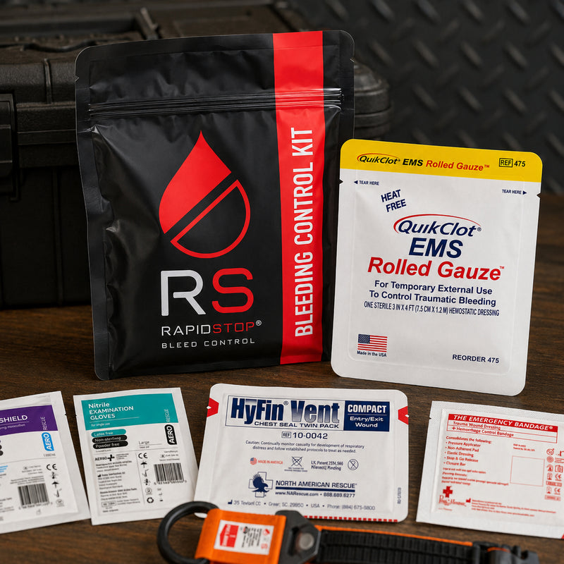 Close presentation of the RapidStop Medium trauma kit with the black bleeding control pouch and QuikClot EMS Rolled Gauze prominently displayed. Additional emergency equipment includes the HyFin Vent Compact chest seal, emergency trauma bandage, nitrile examination gloves, CPR faceshield and part of the orange RapidStop tourniquet.