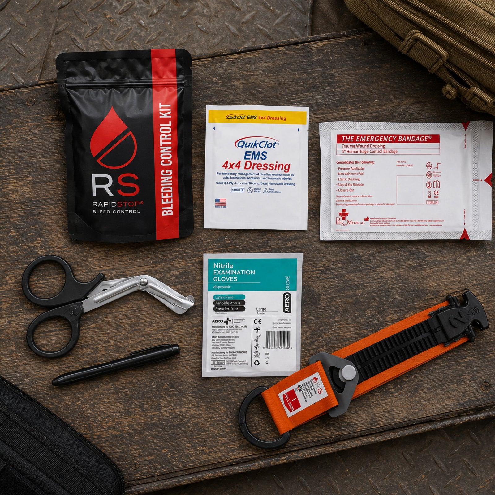 Complete RapidStop Small Bleed Control Kit arranged on a timber work surface. The layout clearly displays the black RapidStop pouch, QuikClot EMS 4x4 haemostatic dressing, 4 inch emergency bandage, examination gloves, trauma shears, marker and distinctive orange and black RapidStop tourniquet.