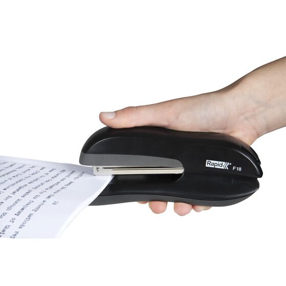Hand holding the Rapid F18 full strip stapler in black while stapling the corner of a printed page