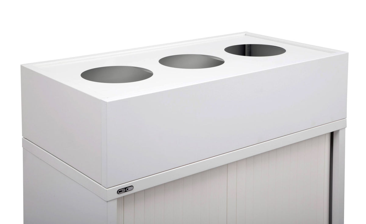Empty white Rapidline Go planter box with three round pot cut-outs, sitting on top of a white tambour door cupboard