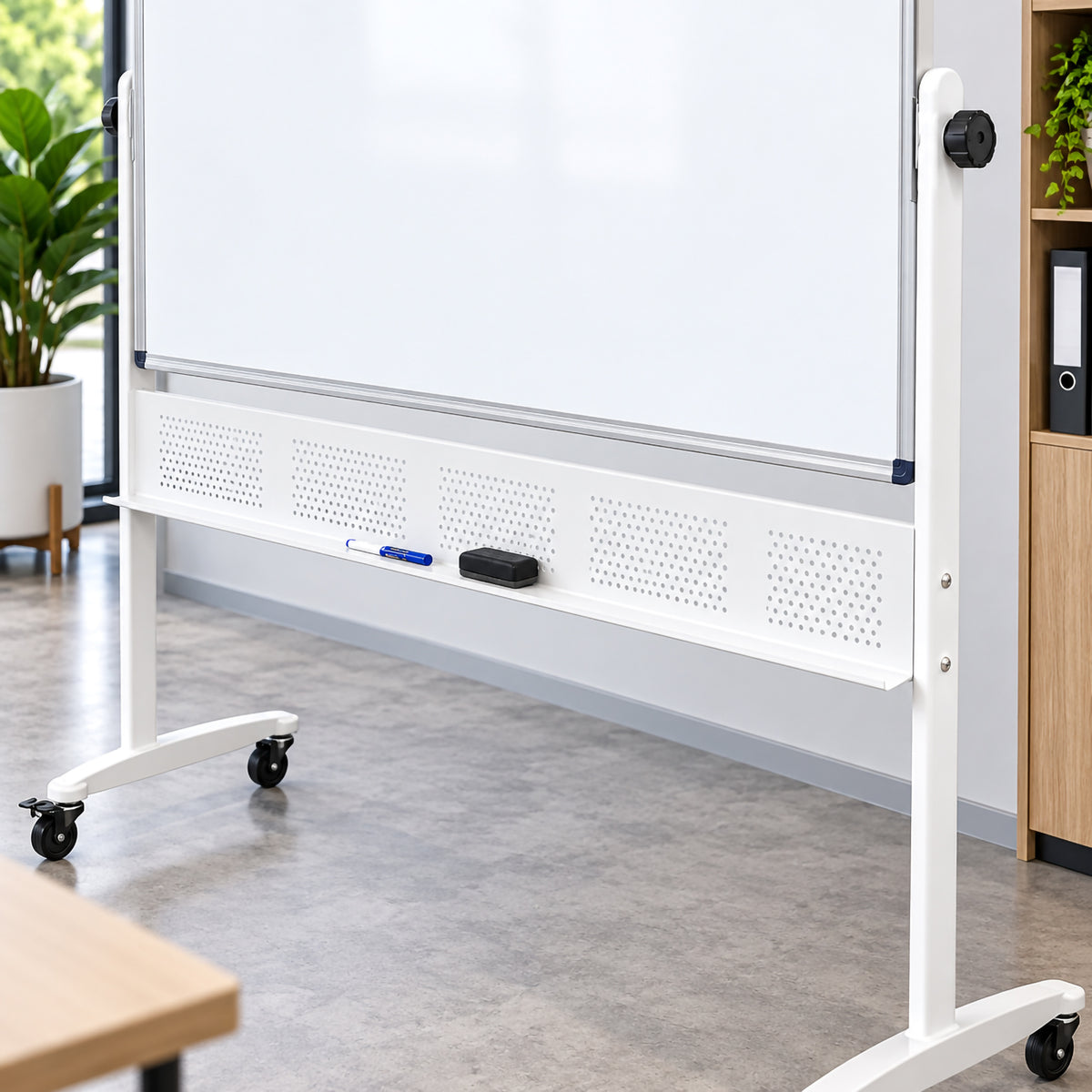 Close up lifestyle view of the Rapidline mobile magnetic whiteboard showing the lower aluminium board edge, perforated support panel, integrated pen tray and sturdy white mobile frame. A marker and eraser sit conveniently on the tray, while the pivot control and castor equipped feet highlight practical features designed for regular workplace use.