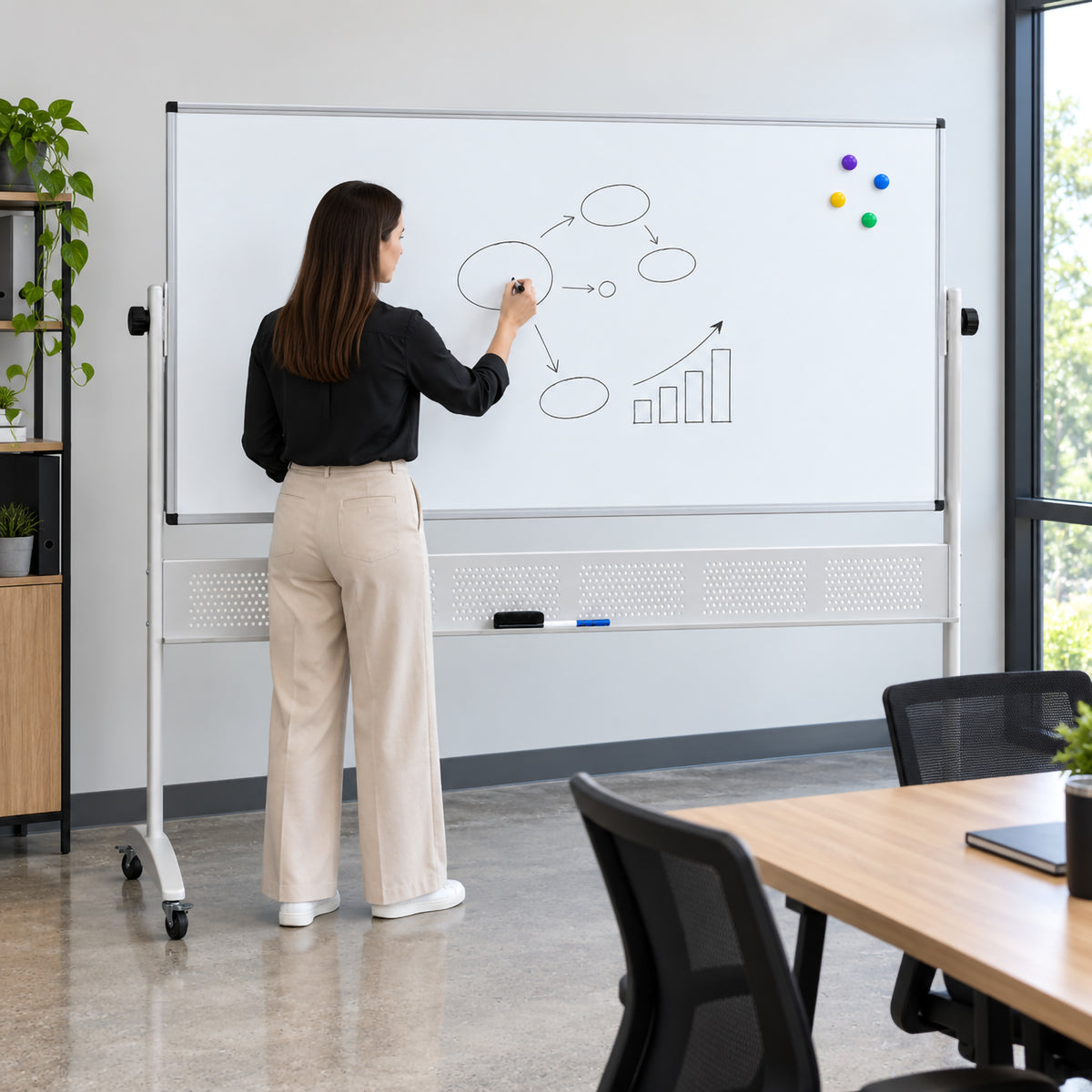 Rapidline Standard Mobile Magnetic Whiteboard 1800 x 1200mm being used in a modern meeting room by a person drawing a workflow and growth chart. The expansive magnetic writing surface provides generous room for detailed brainstorming and presentations, while the aluminium frame, mobile stand and castors demonstrate its suitability for collaborative professional environments.