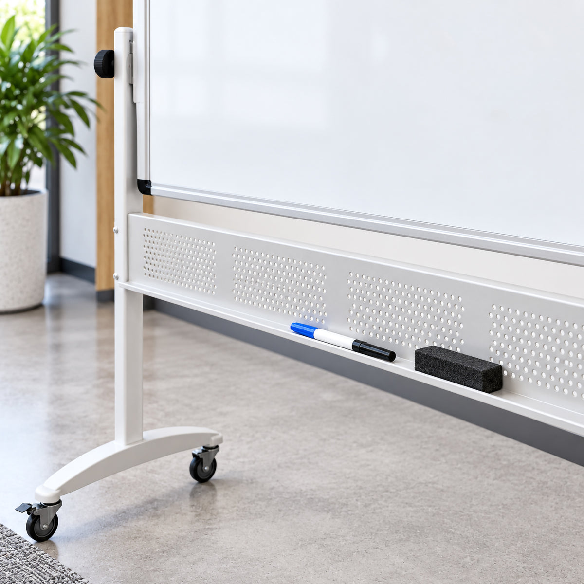Close up of the Rapidline 1800 x 900mm mobile magnetic whiteboard showing the aluminium frame, pivot control, sturdy upright support and integrated accessory tray. Whiteboard markers and an eraser rest conveniently on the tray, while the mobile base and castors highlight the practical design for offices, classrooms and training environments.