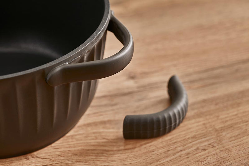 A Resto Ascella casserole with one of its silicone handle pads removed, showing the bare side handle beneath (Resto series image)