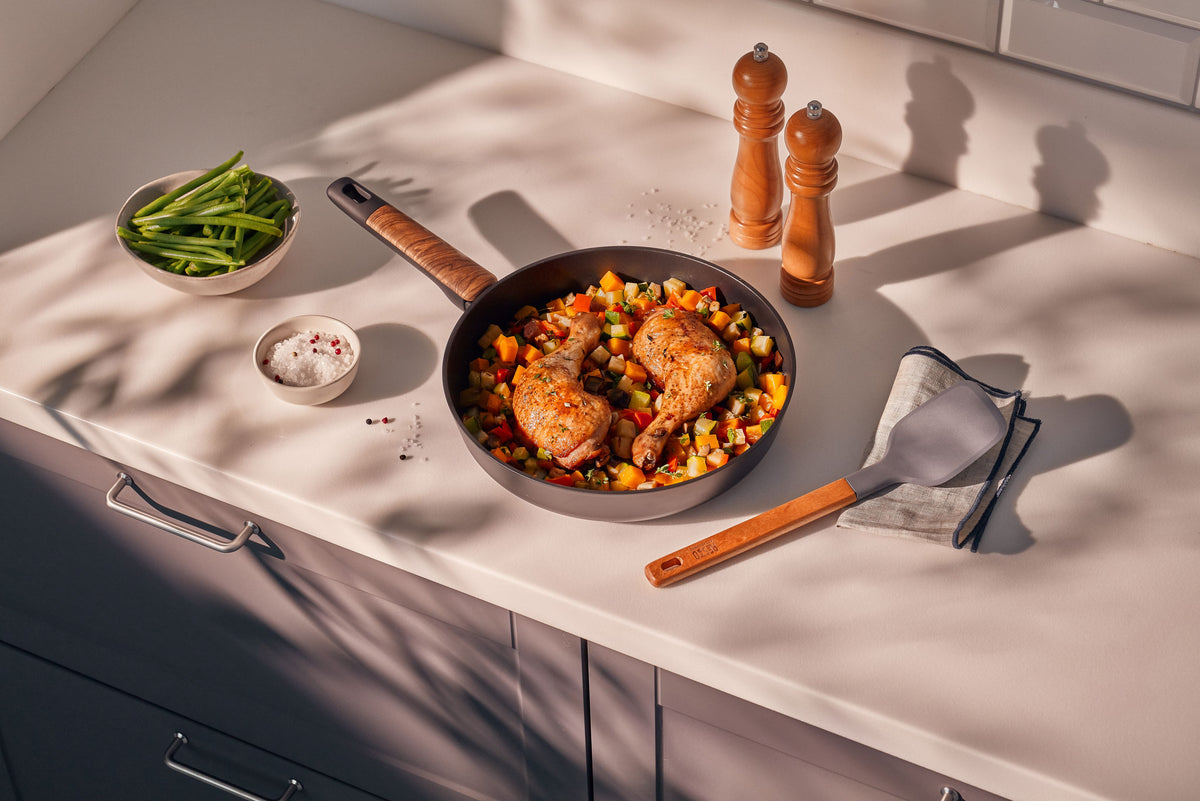 Resto Mon black non-stick frypan in use, filled with chicken and vegetables