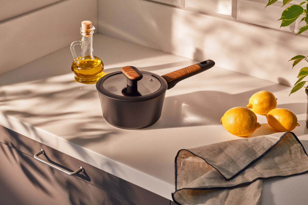 Resto Mon black saucepan with its glass lid on a kitchen bench