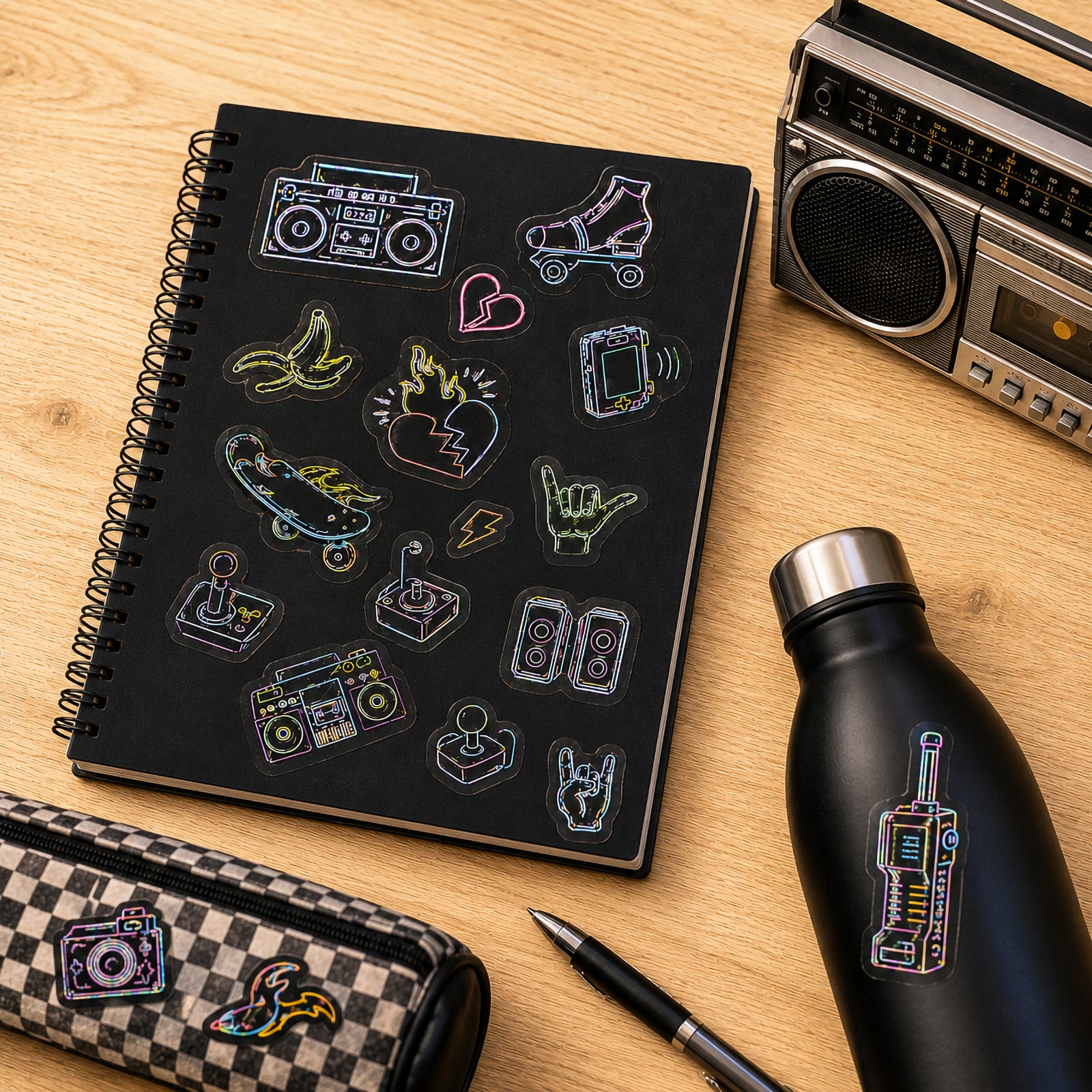 Sticker sheet displayed on a notebook surrounded by retro themed accessories including a cassette radio and stationery. The colourful glow designs showcase classic entertainment and gaming inspired icons.