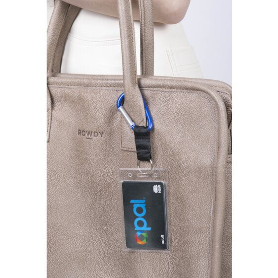 Rexel blue carabiner key ring in use, clipped through the handle of a tan leather bag and carrying a clear card holder with a travel card inside.