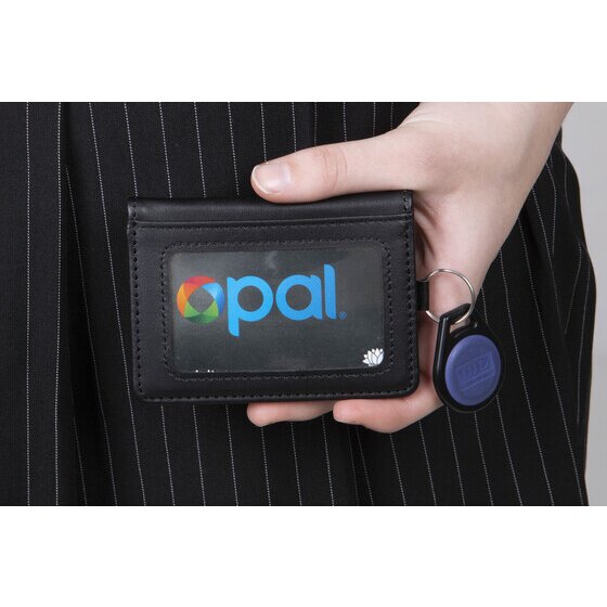 Hand holding a closed black Rexel leatherette wallet with a transport card in the front window and a key fob on the ring