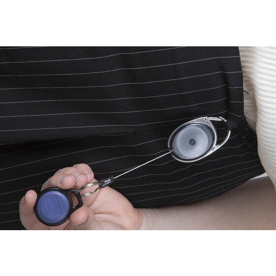 Rexel charcoal snap lock key holder clipped to a dark pinstriped jacket, the cord drawn out to a hand holding a blue oval access fob.