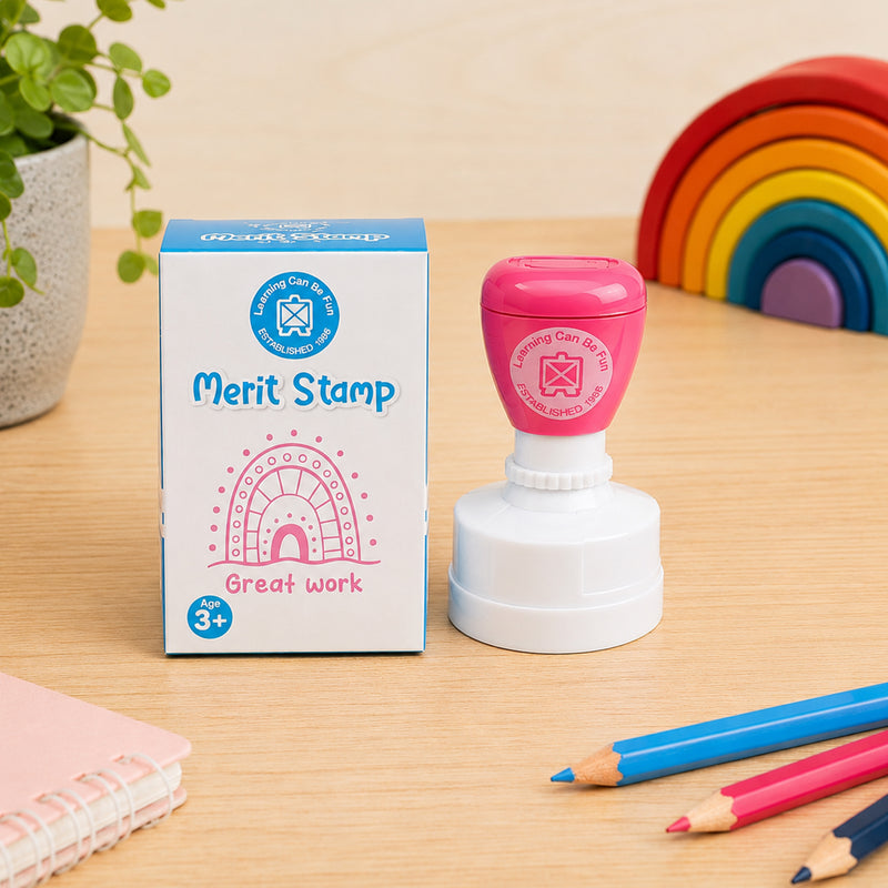 Product packaging and the Sacred Country Sandhill Merit Stamp are presented together on a classroom desk. The image highlights the Great Work message, colourful design and attractive retail presentation, making it ideal for teachers and educators.