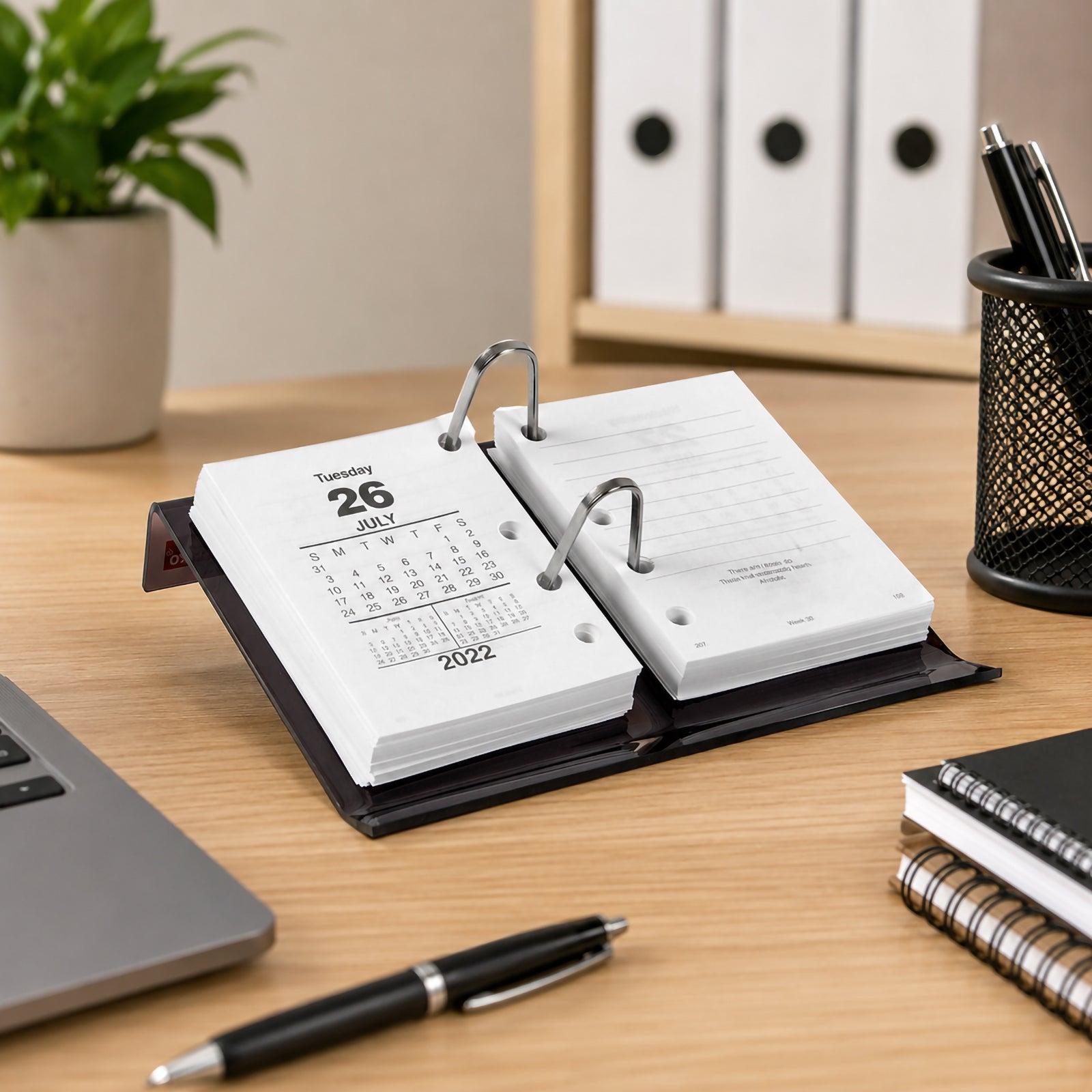 The Sasco Side Opening Desk Calendar Stand is displayed on a tidy office desk with compatible calendar refill pages installed. Stationery, folders and desktop accessories create a professional environment that highlights the stand's practical design and easy readability.