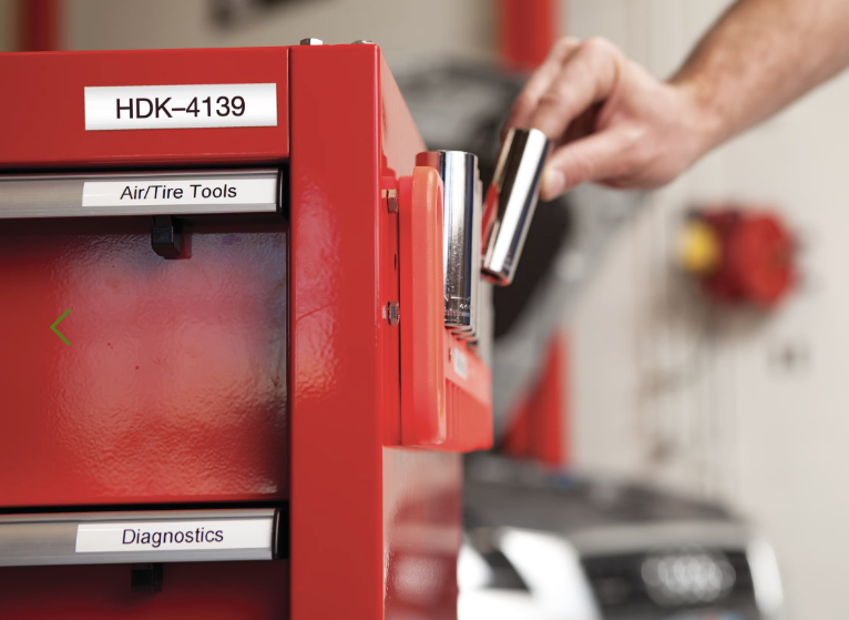 Red diagnostic tool with 'HDK-4139' label, hand holding a metallic object in a workshop setting.