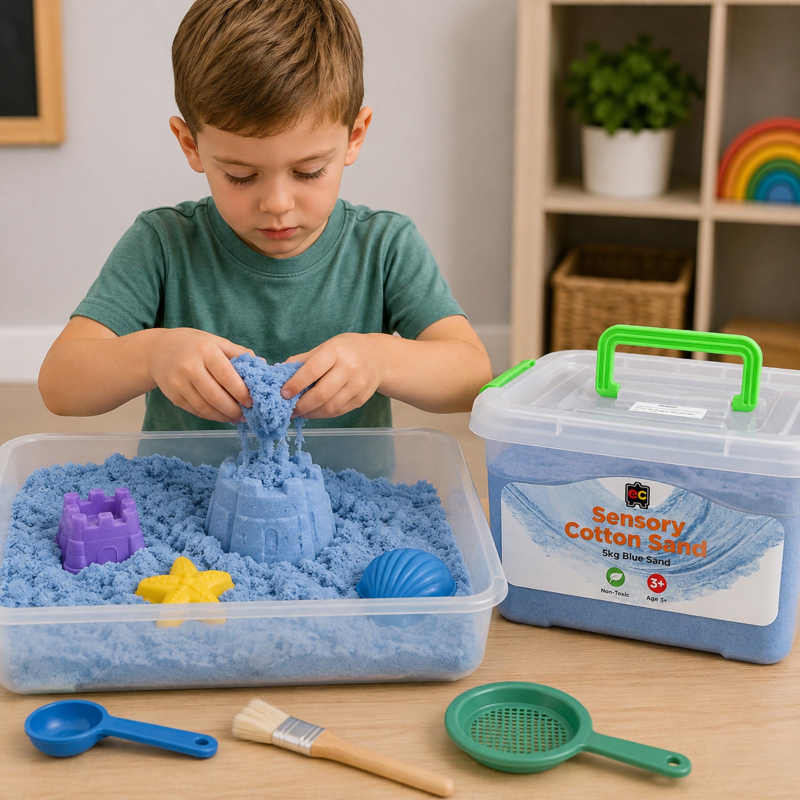 Young child playing with blue sensory cotton sand in a tray using moulds and sensory tools, with reusable 5kg storage tub beside the activity setup.