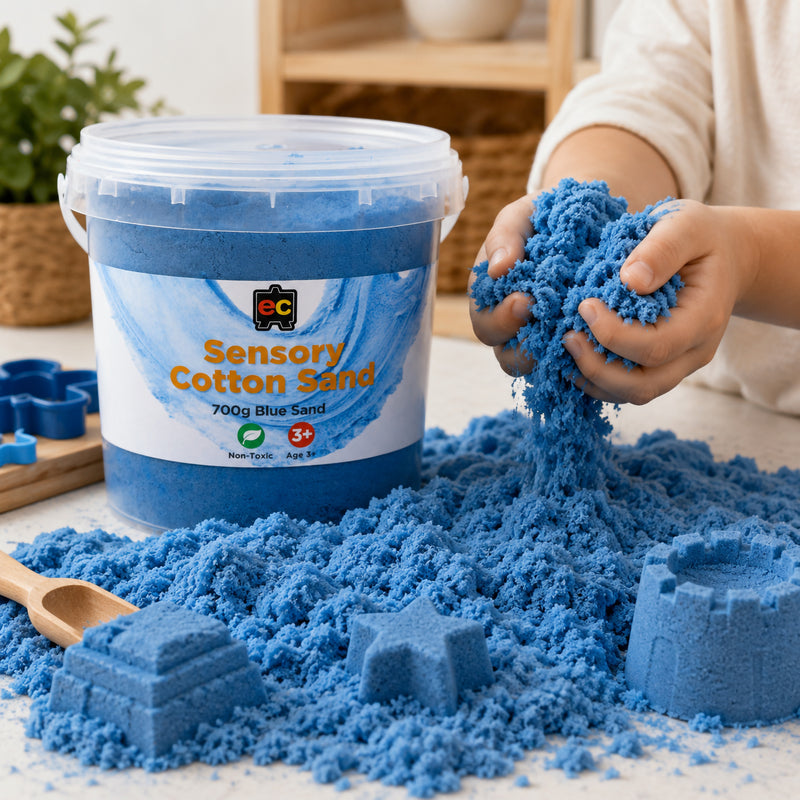 Child holding and stretching vibrant blue Educational Colours Sensory Cotton Sand beside moulded sand shapes and reusable storage tub.